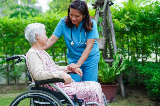 Doctor help Asian elderly woman disability patient sitting on wheelchair in park, medical concept.