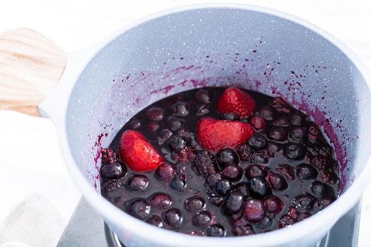 Preparing mixed berry compote from frozen berries in a nonstick cooking pot.