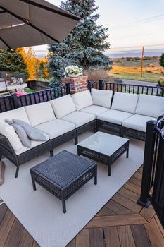 Morning on a summer day. Fully furnished backyard patio with a grill, sitting area, and umbrella.