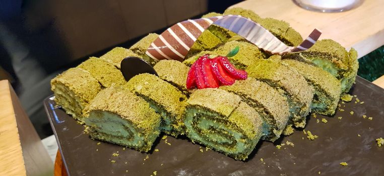 Sponge roll cake with strawberry and chocolate slice and pistachio, food photography concept in fancy restaurant