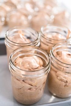 Scooping mixture into the small glass jars to make homemade chocolate ice cream.