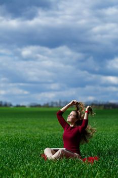 Young successful woman is sitting on green grass with a laptop in her hands. Rest after a good working day. Work on the nature. Student girl working in a secluded place. Workplace in nature