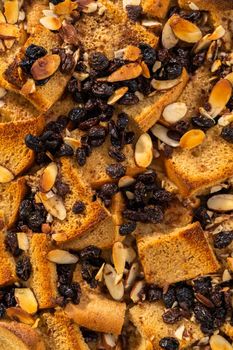 Cooling freshly baked bread pudding with raising and almond slivers in a white casserole dish.