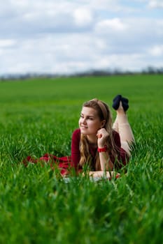 Young beautiful woman student with a laptop lies on the grass. Work outdoors.