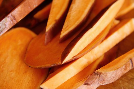 Still life. Selective focus on wedges of sweet potatoes on wooden table. Copy ad space for text. Healthy raw vegan food. Banner. Top view. Organic batata enriched in wholesome nutrients