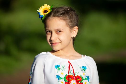 A little Ukrainian and Belarusian girl in an embroidered shirt on a summer background.