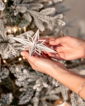 the concept of holidays and people - close-up of hands and a toy decorating the Christmas tree