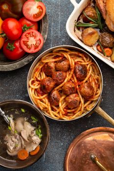 Dining table with traditional tasty homemade dishes: chicken soup, meatballs with spaghetti, roasted chicken with potatoes. Classic home natural comfort food for family meal dinner, top view