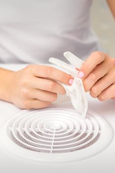 Beautician, doctor, or manicurist holds white latex protective gloves while preparing to wear them before providing services