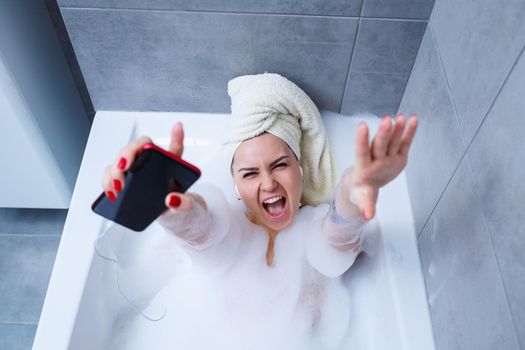 Beautiful young woman listening to music and singing while taking a bath at home. Relax after a hard day. Spa relaxing procedure.