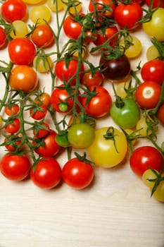 Little red, yellow, green and black cherry tomatoes on white table, nature background, pattern, flat lay with copyspace.