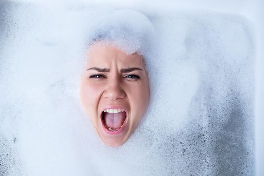 Closeup portrait of a girl in a bathtub and white foam around her face. Different emotions, grimaces, woman smile