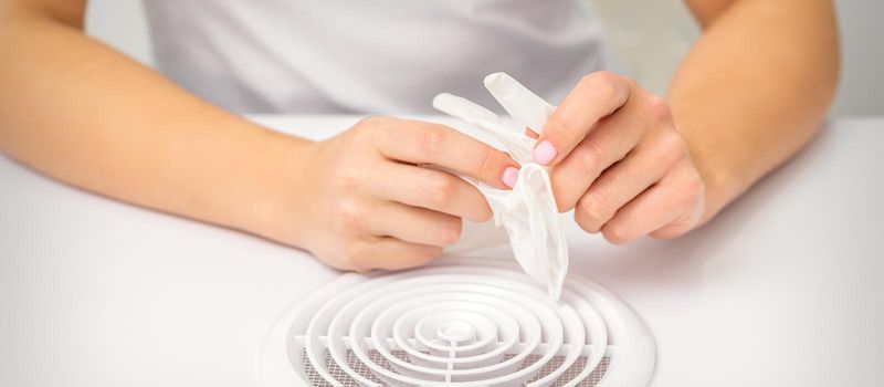 Beautician, doctor, or manicurist holds white latex protective gloves while preparing to wear them before providing services