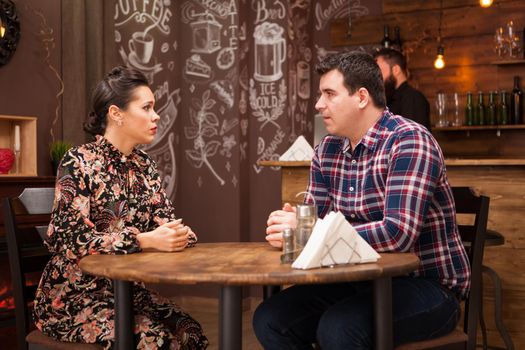 Young couple sitting in a restaurant talking and having a good time.