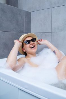 Young woman in a hat and sunglasses takes a bath at home. Relax after a hard day. The spa is a relaxing procedure.