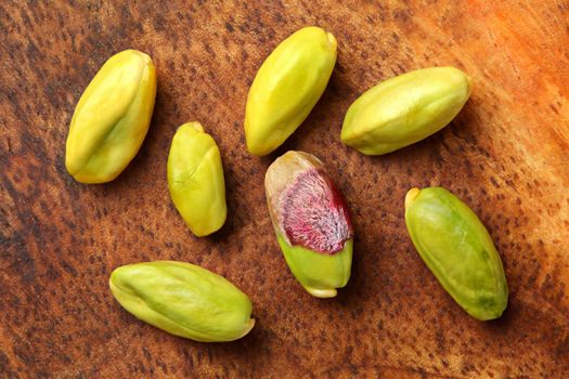 Close up photo - peeled green pistachios on wooden board. View from above