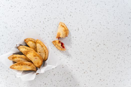 Flat lay. Freshly baked sweet cherry empanadas in the air fryer on the kitchen counter.