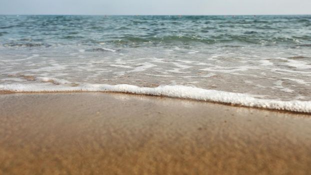 Low angle / ground level photo of wet sand on the beach, sea in background.
