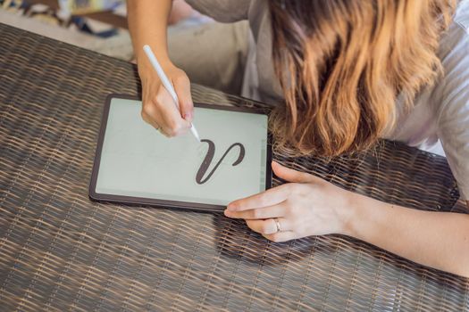 Calligrapher Young Woman writes phrase on digital tablet. Inscribing ornamental decorated letters. Calligraphy, graphic design, lettering, handwriting, creation.