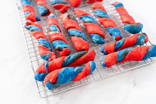 Drizzling white glaze on top of patriotic cinnamon twists. and decorating with star sprinkles.