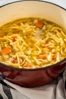 Cooking chicken noodle soup with kluski noodles in an enameled dutch oven.