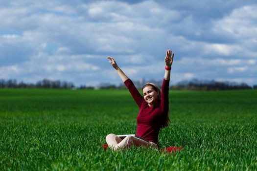 Young successful woman is sitting on green grass with a laptop in her hands. Rest after a good working day. Work on the nature. Student girl working in a secluded place. Workplace in nature
