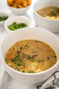 Serving creamy wild mushroom soup made out of dehydrated wild mushrooms in white bowls with sourdough bread.