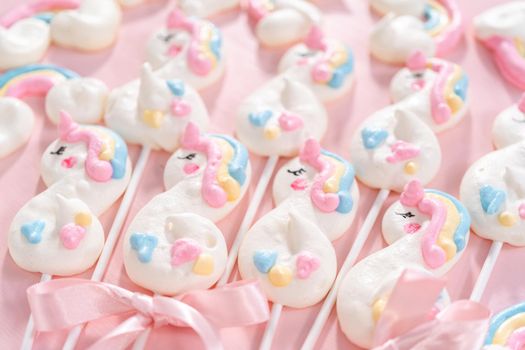 Gourmet unicorn theme meringue pops on a pink background.
