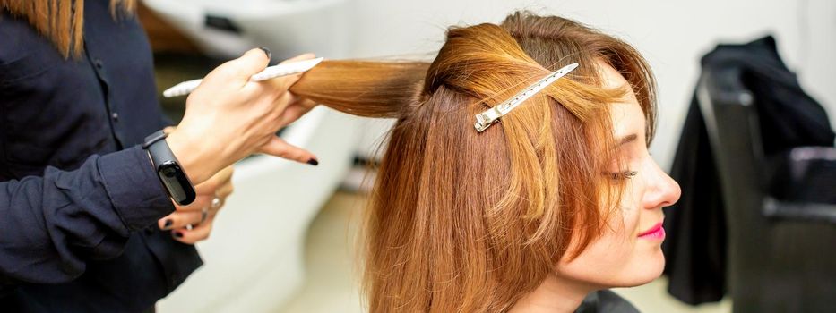 The female client receiving a haircut at the beauty salon, young woman enjoying getting a new hairstyle