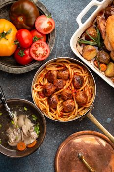 Dining table with traditional tasty homemade dishes: chicken soup, meatballs with spaghetti, roasted chicken with potatoes. Classic home natural comfort food for family meal dinner, top view