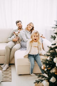 Happy family: mom, dad and pet. Family in a bright New Year's interior with a Christmas tree.