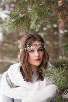 Beautiful bride in a white dress with a bouquet in a snow-covered winter forest. Portrait of the bride in nature.