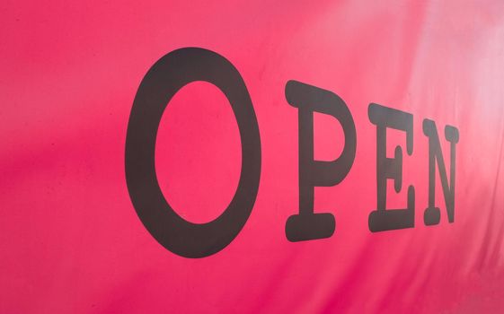 Pink and black open sign in a shop window