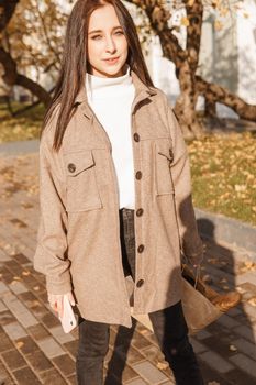 A stylish brunette woman walks around the autumn city. The season is autumn.