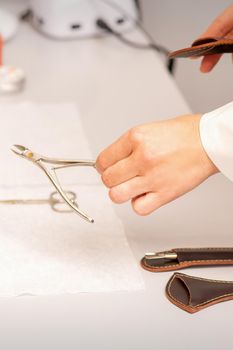 Nail nippers in the hand of female manicure master putting to the towel before nail care in manicure salon