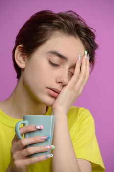 Bored young girl with cup of coffee suffering headache. Eyes closed, magenta background