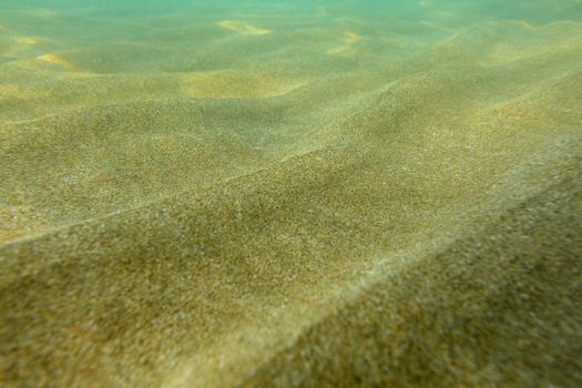 Underwater photo, shallow sea with sand "dunes" lit by sun.
