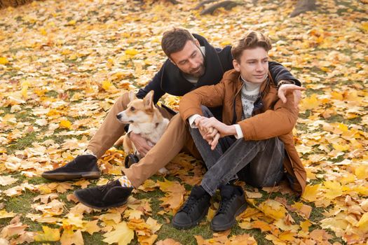 Father and son with a pet on a walk in the autumn park.