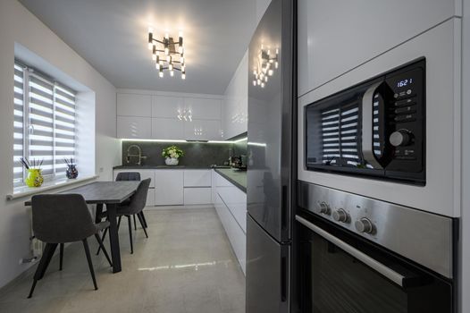 Modern trendy white and grey kitchen interior after renovation, with granite counter top and marble floor, closeup to oven