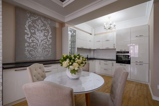 Luxury white modern kitchen with pink and white walls and laminated wooden flooring in studio apartment