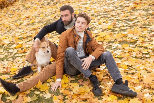 Father and son with a pet on a walk in the autumn park.