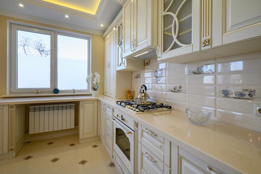 Classic white and beige luxurious kitchen in studio apartment interior