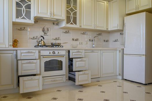 Classic white and beige kitchen furniture with retracted drawers in studio apartment