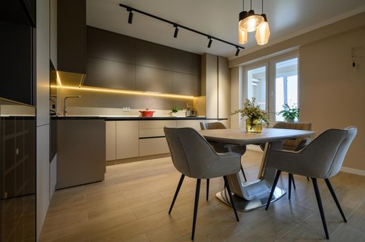 Modern grey luxurious kitchen in studio apartment interior, closeup to dining table