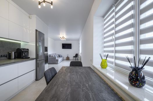 Luxurious modern trendy white and grey kitchen interior after renovation, with granite counter top
