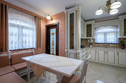 White classic cozy kitchen and dining room in city house interior