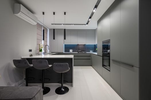 Elegant white and grey luxury kitchen, dining room with kitchen bar and stools in studio apartment interior
