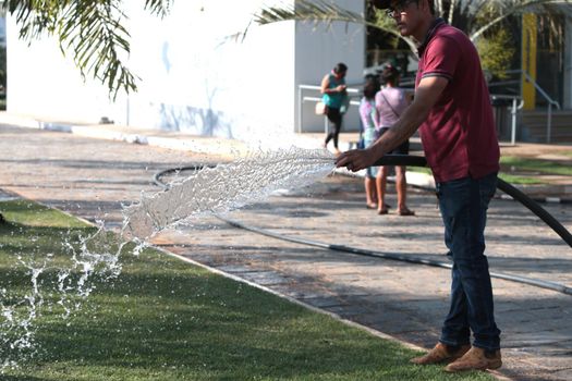 santana, bahia, brazil - september 13, 2022: gardener pours water with a hose in a garden of a public square in the city of Santana.