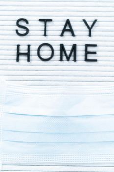 STAY HOME sign on message board with a blue medical mask.