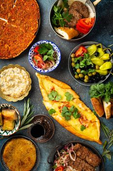 Traditional Turkish food, assorted dishes and mezze appetizers on rustic background from above. Pide, Lahmacun, meat kebab, Turkish meatballs, sweet baklava and Kunefe. Middle East cuisine, top view